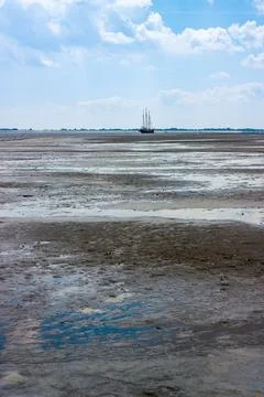 Three-masted sailing ship, textured mudflats of the Wadden Sea. Stock Photos