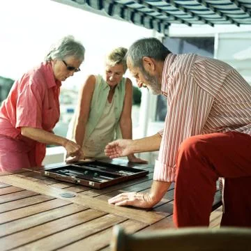 Three mature friends playing backgammon Stock Photos