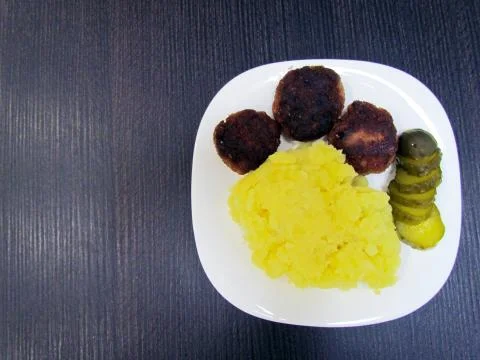Three meatballs, mashed potatoes and pickled cucumbers Stock Photos