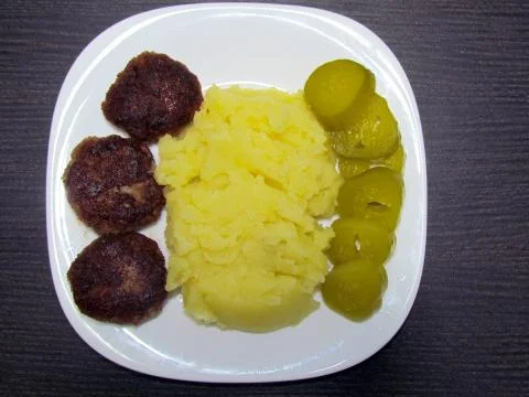 Three meatballs, mashed potatoes and pickled cucumbers Stock Photos