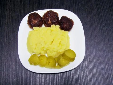 Three meatballs, mashed potatoes and pickled cucumbers Stock Photos