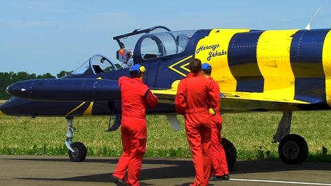 Three mechanics in red overalls inspect L-39 aircraft after flight. Close-up. Stock Footage 106772173