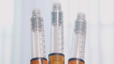 Three medical injection pens showcasing clear fluid cartridges macro Stock Footage 340254537