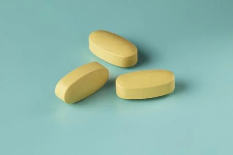 Three medicinal caplets on cyan background Stock Photos