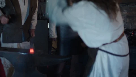 Three Medieval Blacksmiths Work at an Anvil Stock Footage 129553815