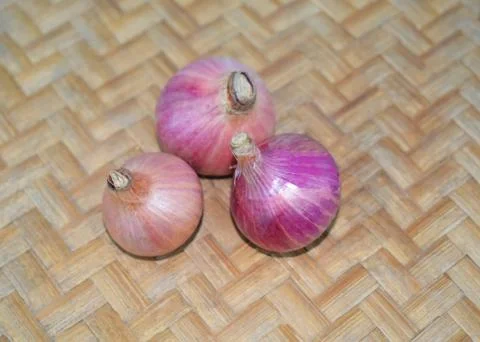Three medium sized red colored fresh onion gathered together on a wood backgr Stock Photos