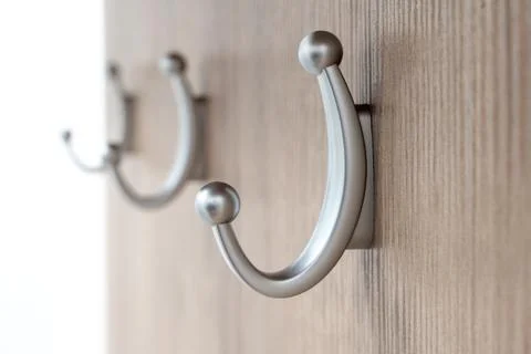 Three medium sized, silver colored coat hangers attached to a wooden board with Stock Photos
