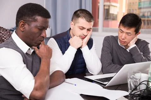 Three men are looking on documents and talking about it together Stock-Fotos