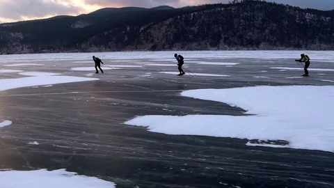 Three men are skating on the ice of frozen Lake Baikal during beautiful sunset. Stock Footage 77858751