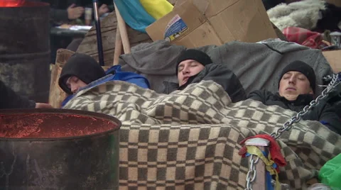 Three men are sleeping around the campfire on the Central square. Stock Footage 41999718