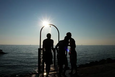 Three men are standing under a shower head, kissing each other Stock Photos