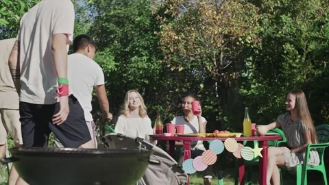 Three men bring just cooked bbq sausages and meat to his girlfriends Video stock 143480493