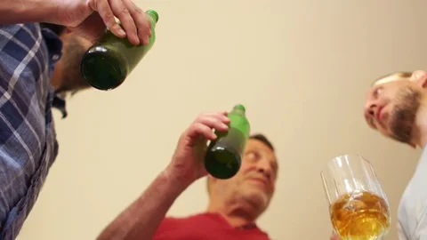 Three men drink beer. Two of the bottles and the third from a glass goblet. They Stock Footage 91024957