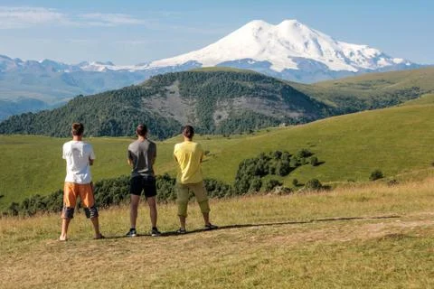 Three men enjoy the view of the mountain before the future ascent. Stock Photos