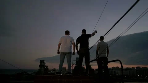 Three men epic stand on the edge of a rooftop overlooking the city Video stock 151646363