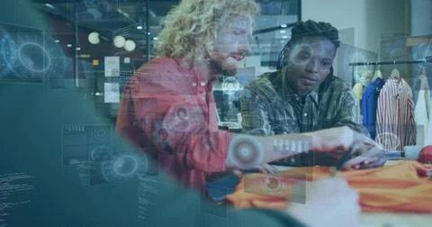 Three men examining orange garment at showroom table, using tablet and Stock Photos