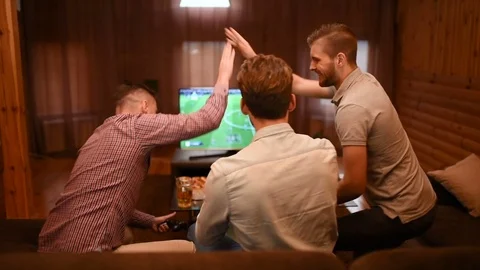 The three men with a game console play in football and drink a beer. slow motion Video stock 83802340