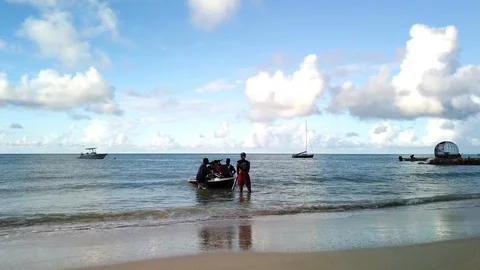 Three men loading jet ski on trailer and pulling it out of blue ocean Stock Footage 124295535