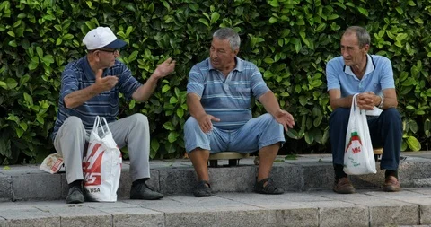 Three men relaxing and talking at city square of Plovdiv, Bulgaria Vidéo 93554743