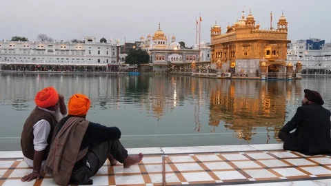 Three men sit by the pool at golden temple in amritsar- 4K 60p Stock Footage 114740718