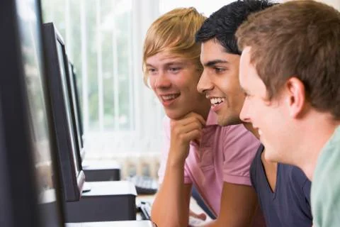 Three men sitting at a computer terminal (high key) Stock-Fotos