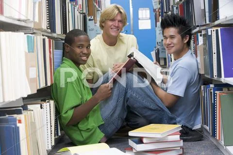 Three men sitting on floor in library with books Stock Photos