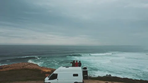 Three men sitting on top of van drone moves above them Stock Footage 203598987