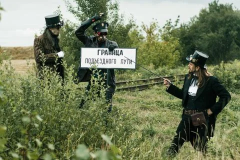 Three men in steampunk suits pose near an abandoned railway Stock Photos