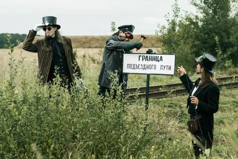 Three men in steampunk suits pose near an abandoned railway Fotos Stock