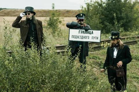 Three men in steampunk suits pose near an abandoned railway Fotos Stock