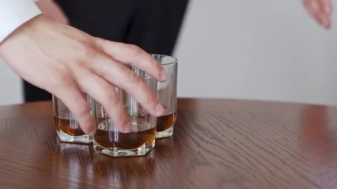 Three men take away whiskey glasses from a table. Stock Footage 221017006