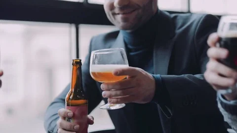 Three men toast with the mugs of beer, smile to each other and drink it Video stock 74800941