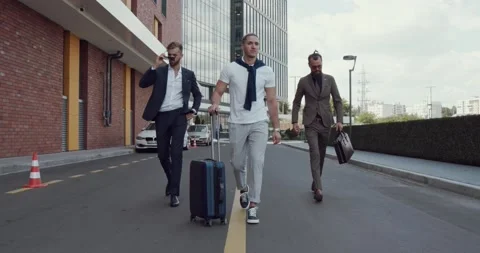Three men walk down the street. A man with a travel bag. Stock Footage 139284296