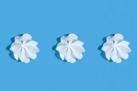 Three meringues with shadow on a blue background. Stock Photos
