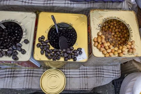 Three metal cans with different colored nuts and a spoon in the middle 스톡 사진