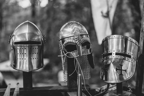 Three metal helmets are displayed on a stand, one of which has a cross on it Stock Photos