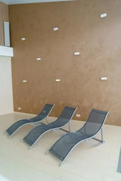 A three metal lounge chairs in empty room Stock Photos