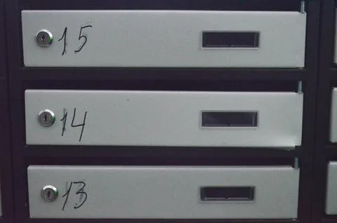 Three metal mailboxes with numbers on them.  Stock Photos