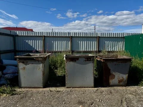 Three Metal Trash Bins in front of Corrugated Fence Stock Photos