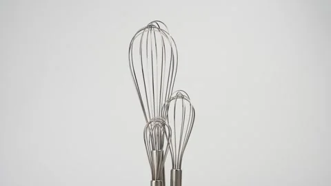 Three metal whisks standing together against white background Stock Footage 343293916