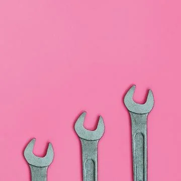 Three metallic spanners lie on texture background of fashion pastel pink co.. Stock Photos