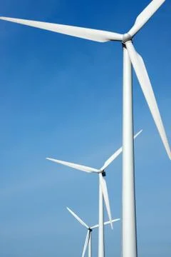 Three mighty windmills in a row against a blue sky. Stock Photos