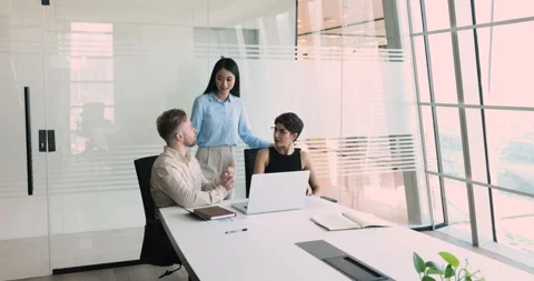 Three millennial colleagues working on project together gathered in office Stock Footage 248502322