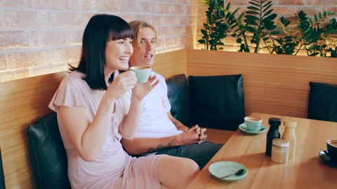 Three millennial friends chat over coffee in cafe on wood bench in Australia dur Stock Footage 199462522
