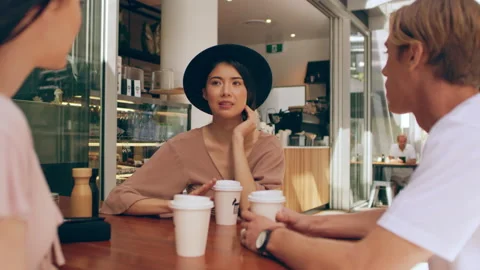 Three millennial friends chat seriously about life events while sipping coffee o Stock Footage 199453052