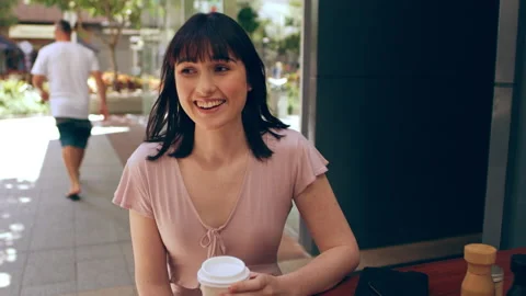 Three millennial friends chat while drinking coffee and tea outside a cafe in Au Stock Footage 199455514