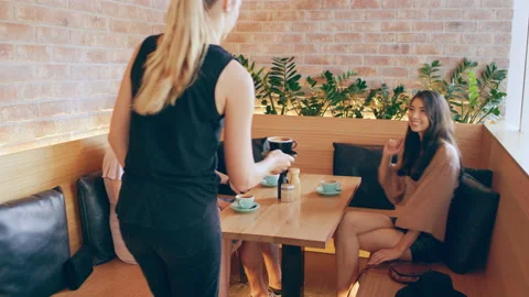 Three millennial friends drink coffee in cafe on wood bench in Australia during Stock Footage 199458093