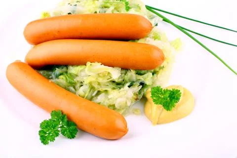 Three mini wieners on fried cabbage with mustard Stock Photos