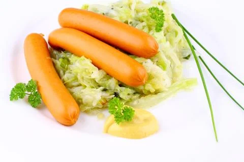 Three mini wieners on fried cabbage with mustard Stock Photos