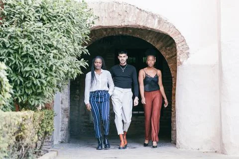 Three models walk through the archway of a building Stock Photos